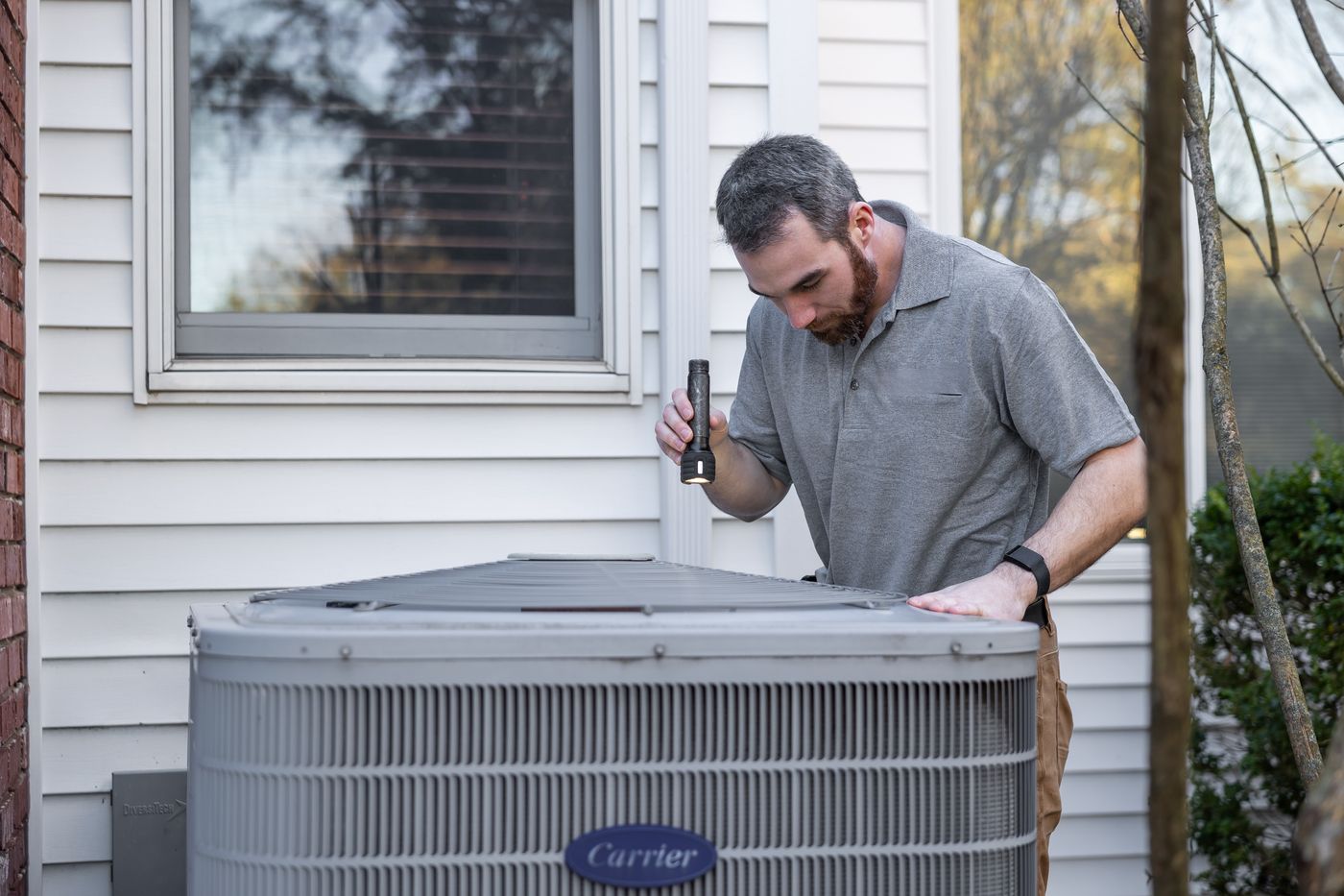 HVAC technician inspecting a residential condenser